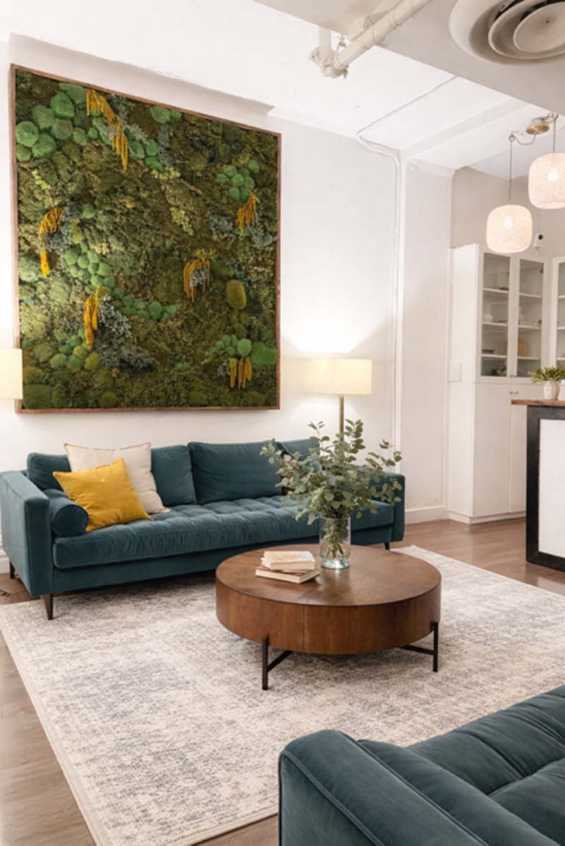 The welcoming lobby of Holistic Wellness NYC with moss wall art and teal sofas